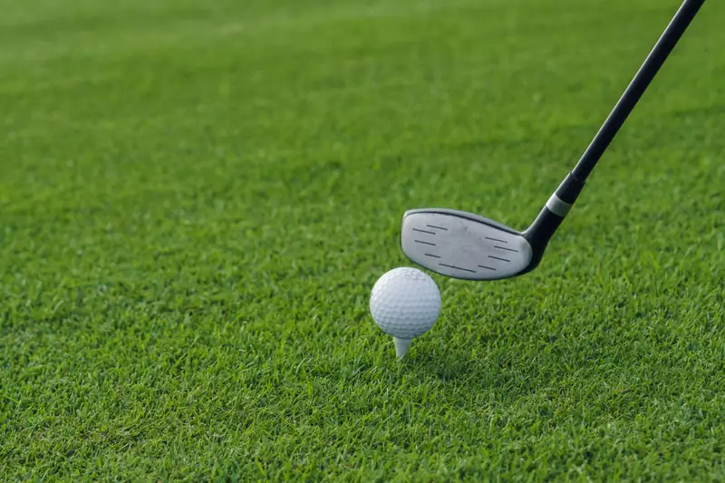 Une balle de golf sur un tee, à côté d'un club