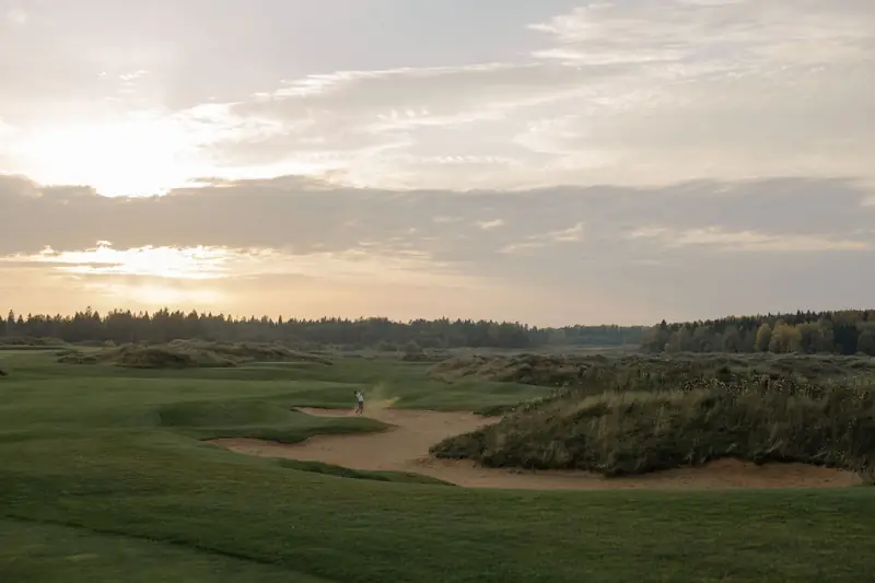 Un parcours de golf au lever du soleil, entre les dunes