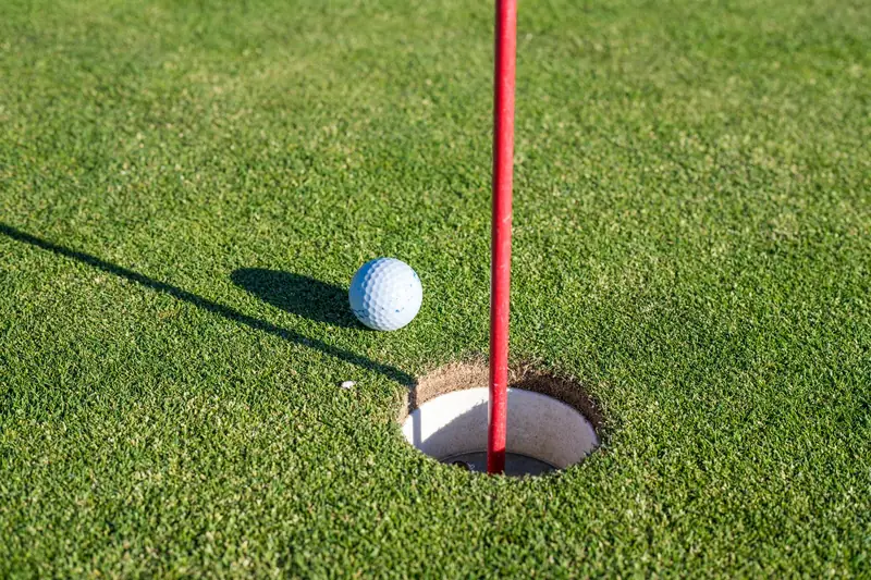 Une balle de golf près du trou, sur le green